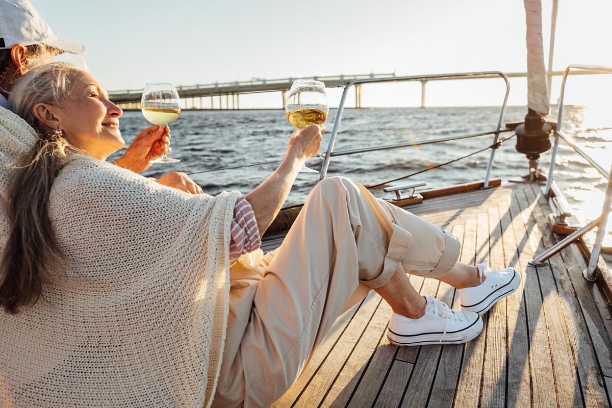 A couple relaxing with wine on a sailboat at sunset
